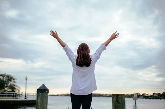 Foto de mujer alzando los brazos en paisaje para el diplomado de Conocimiento de si mismo